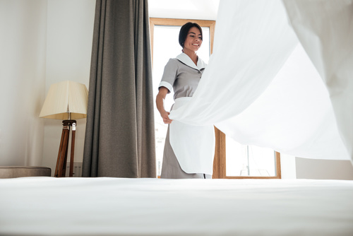Hotel maid changing bed sheet